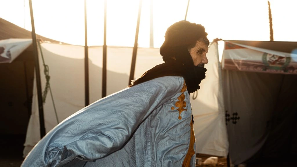 Field photograph of a Tuareg community radio broadcaster at dusk in the Sahara